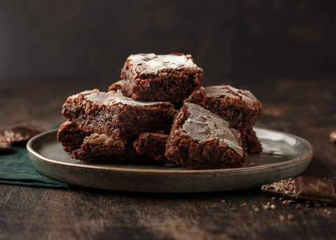 A ceramic plate with deliciously moist brownies stacked in a messy pyramid shape