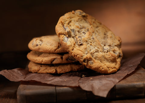 Crispy chocolate chunk cookies stacked high, with one cookie placed at an angle on the side, showing the top of the cookie