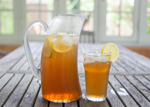 Pitcher and glass of cold iced tea with slices of lemon for garnish