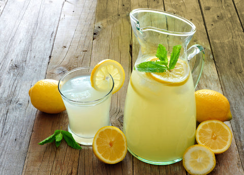 Pitcher and glass of fresh lemonade, with slices of lemon and a sprig of mint garnish
