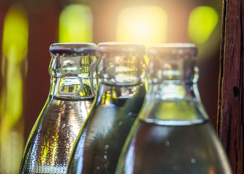 Three glass bottles filled with water, gleaming in the sunlight